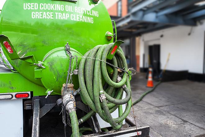 a grease trap being pumped by a sanitation technician in Sherborn